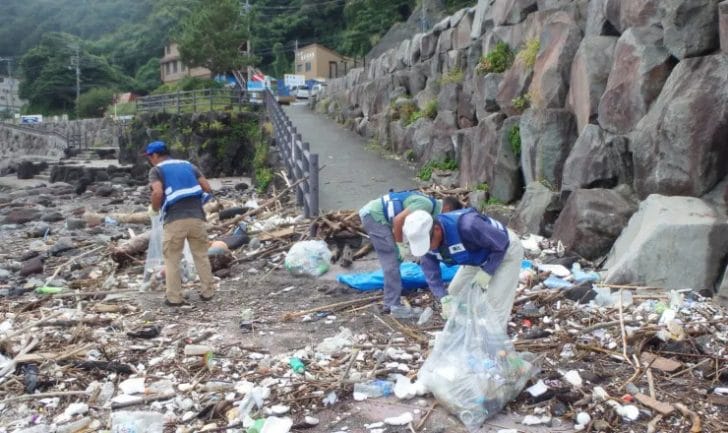 海岸でプラスチックゴミの清掃をする人々